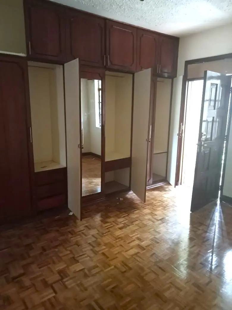 Spacious bedroom with built-in wooden wardrobes and parquet flooring