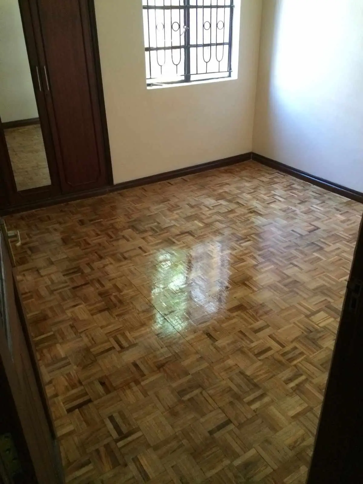 Empty bedroom with herringbone flooring and barred window