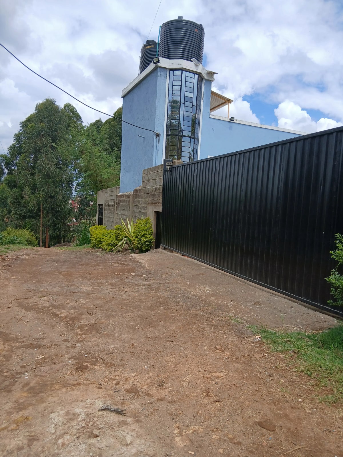 Property entrance with black metal gate and water tank