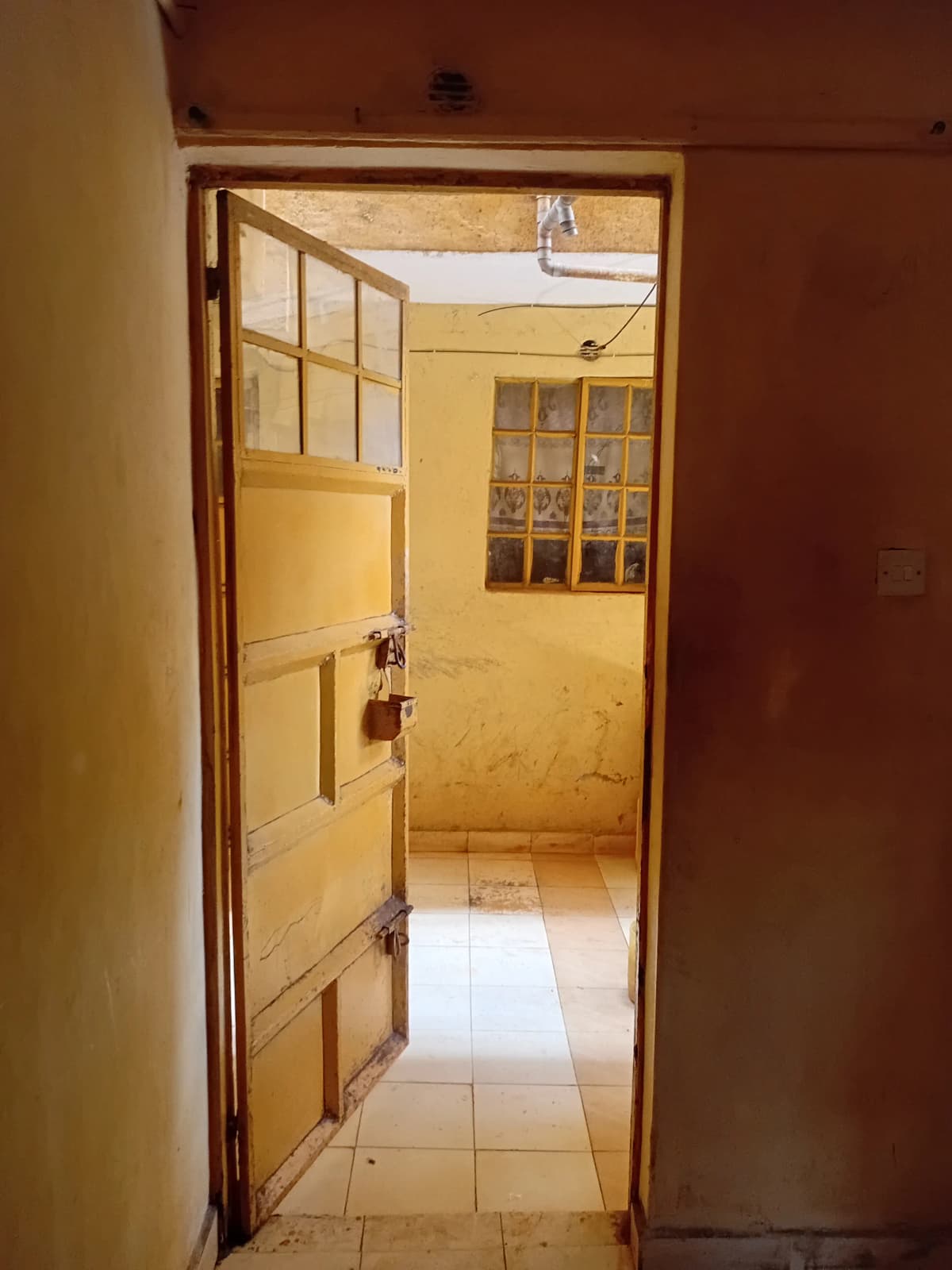 Narrow hallway with wooden door and tiled flooring