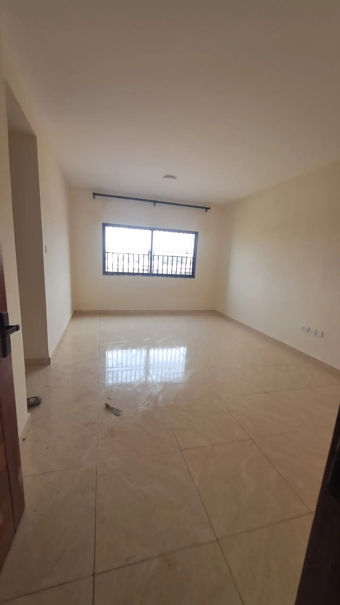 Spacious empty bedroom with polished tile flooring and window