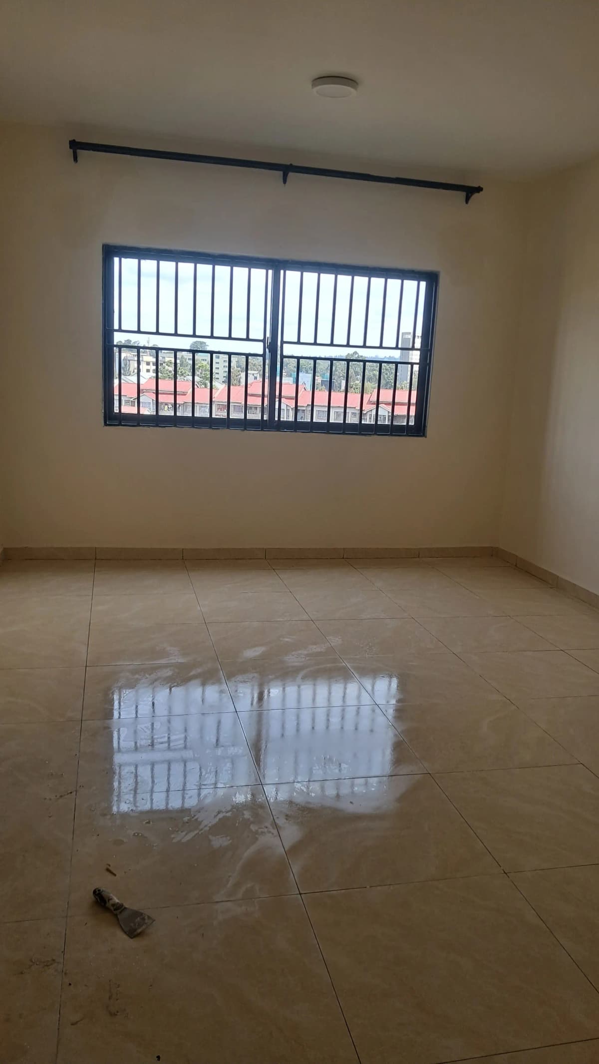 Empty bedroom with barred window, polished concrete floor