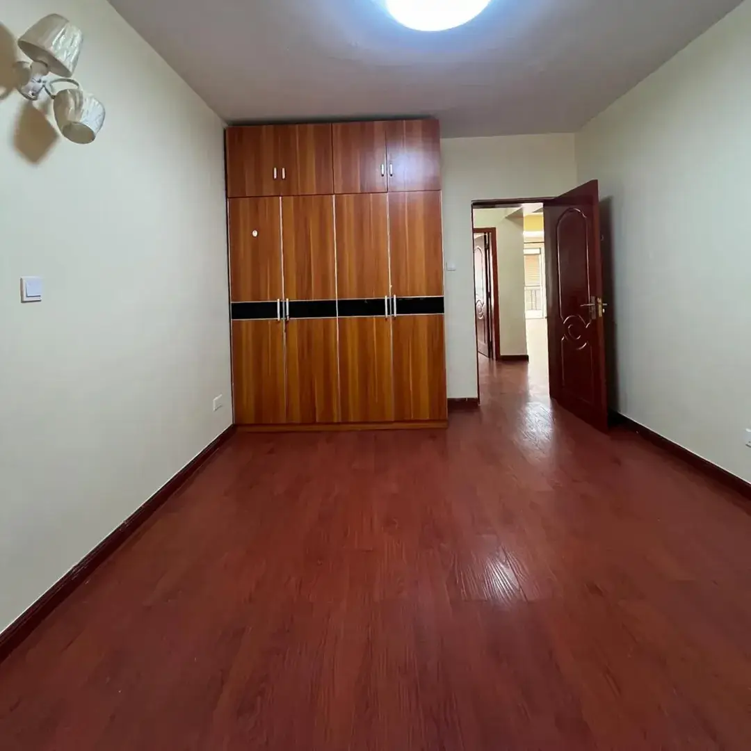 Spacious bedroom with wooden wardrobe and polished floor