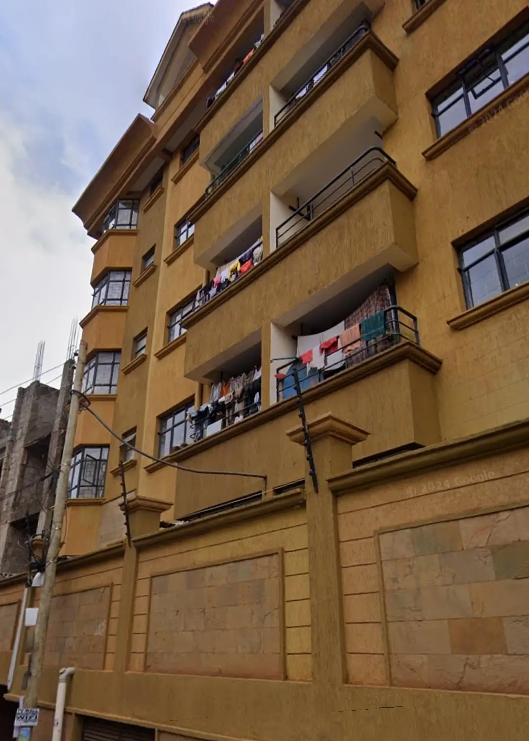 Multi-story residential building facade with balconies and ground-level garage