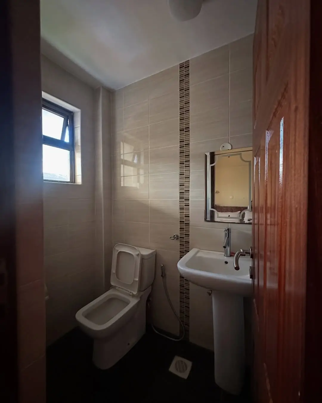 Compact bathroom with toilet, sink, mirror, and tiled walls