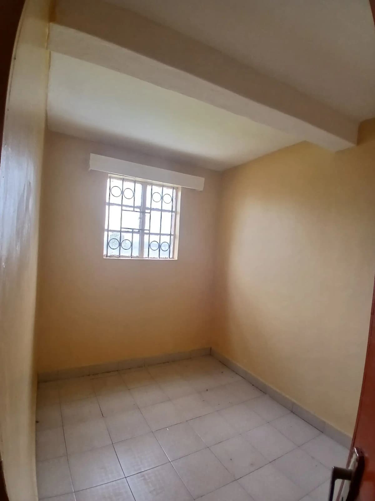 Unfurnished bedroom with barred window and tile flooring