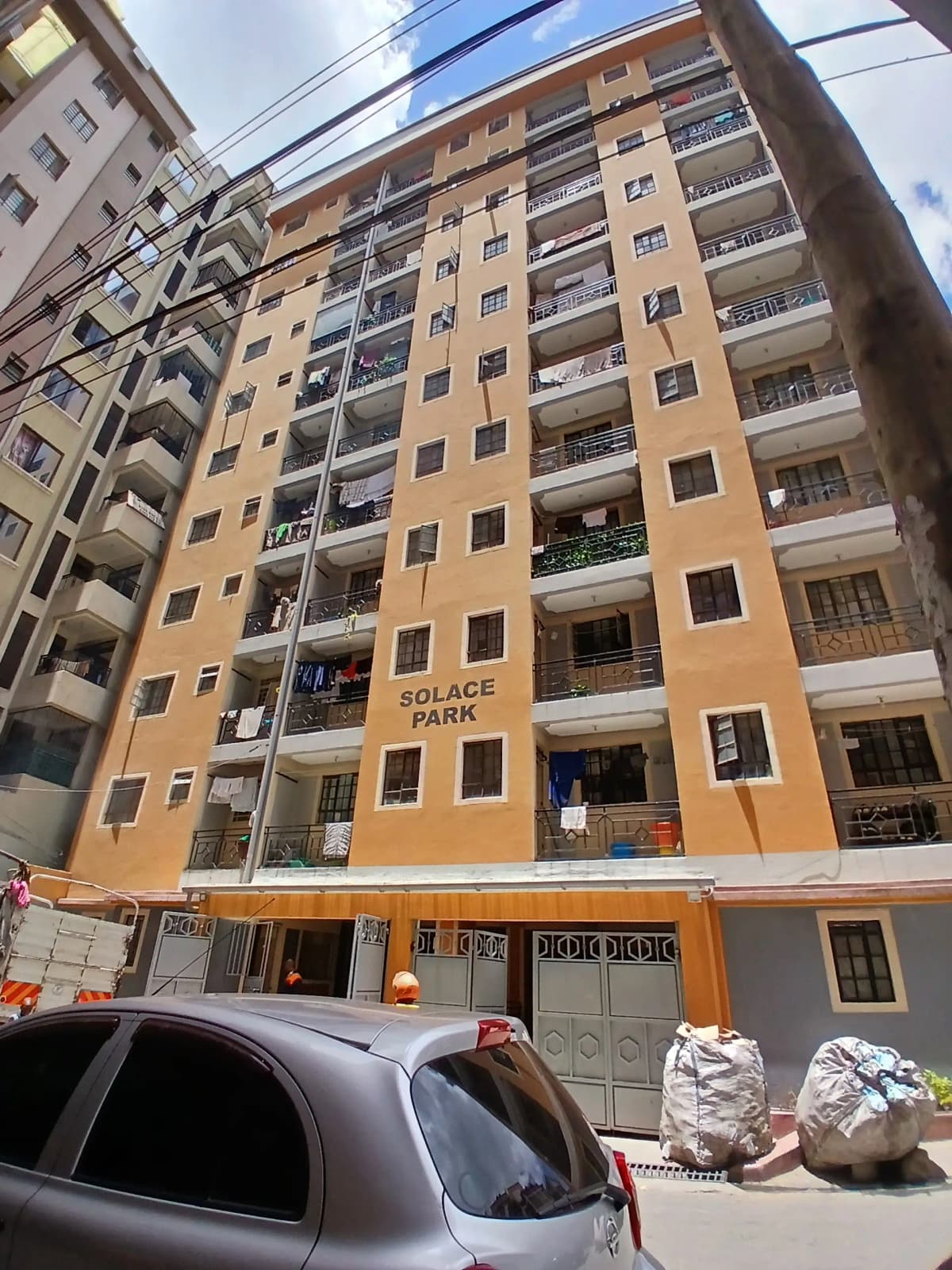 Multi-story residential building facade with balconies and ground-level parking