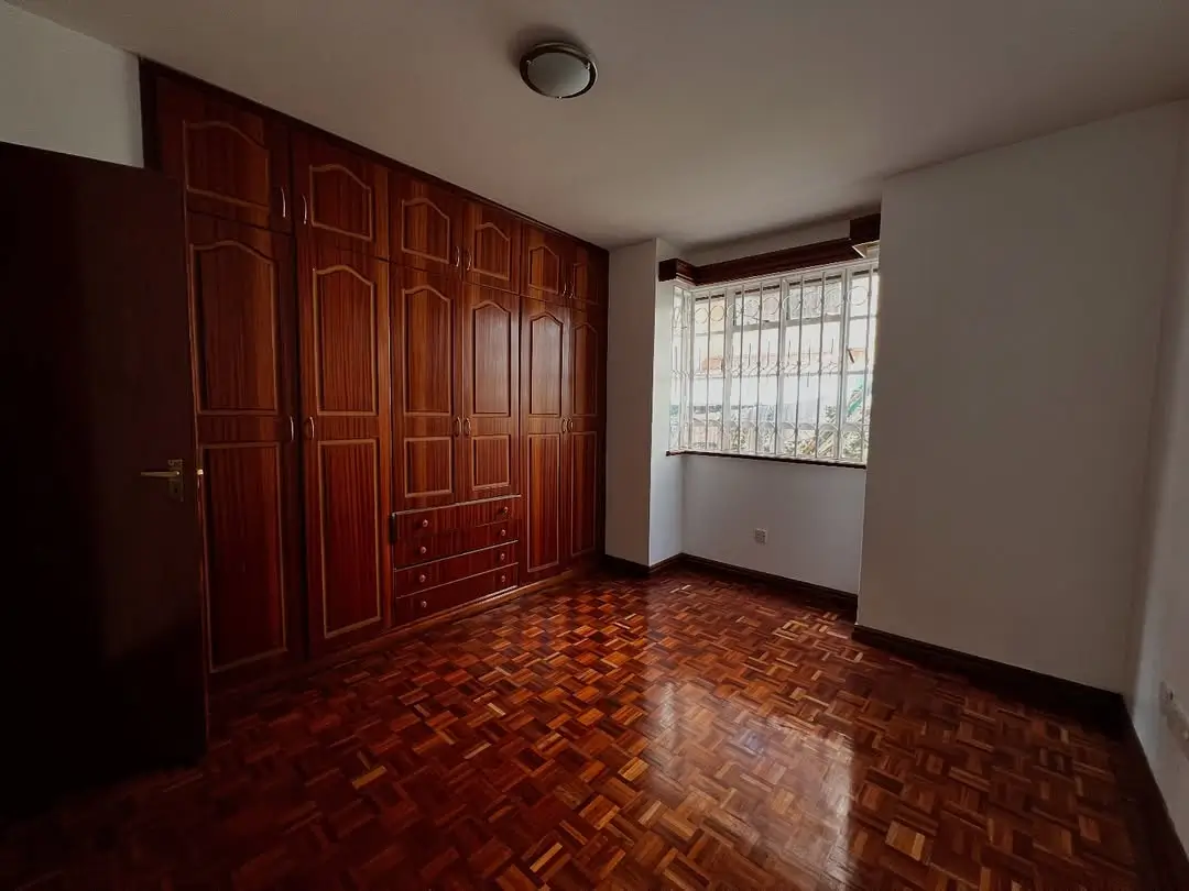 Spacious bedroom with herringbone wooden floors and built-in wardrobe