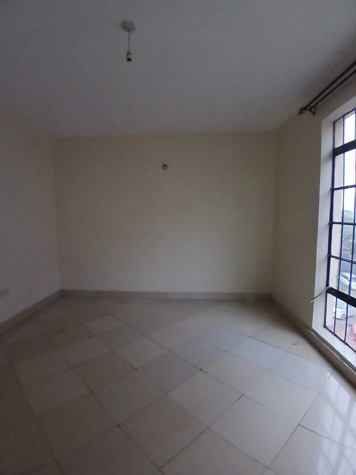 Empty bedroom with tiled floor and barred window