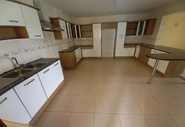 Spacious kitchen with white cabinetry and brown countertops