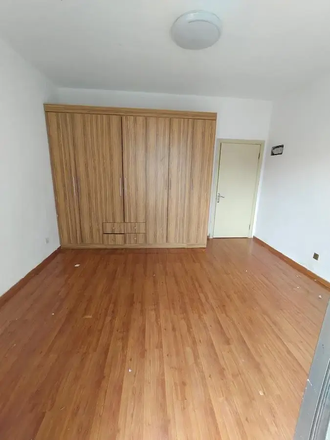Spacious bedroom with wooden wardrobe and laminate flooring