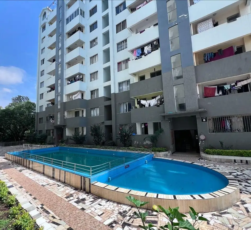 Bright blue oval swimming pool with residential building backdrop