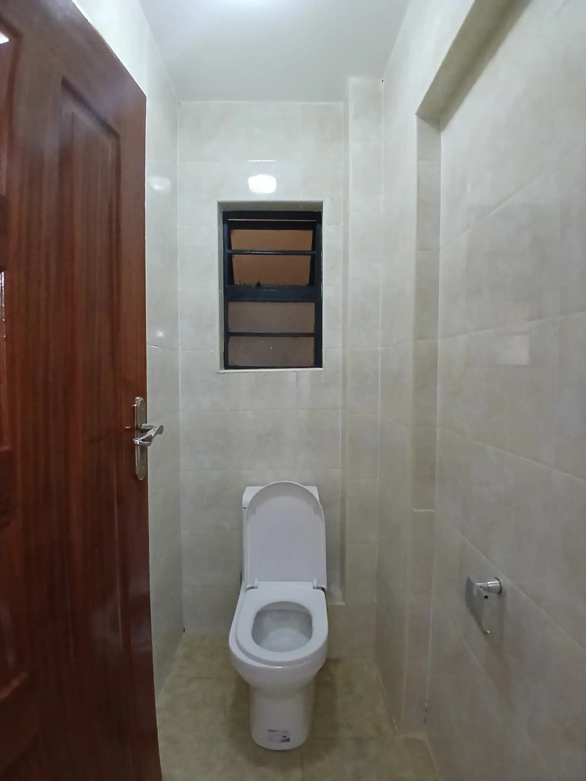 Compact toilet room with wooden door and small window