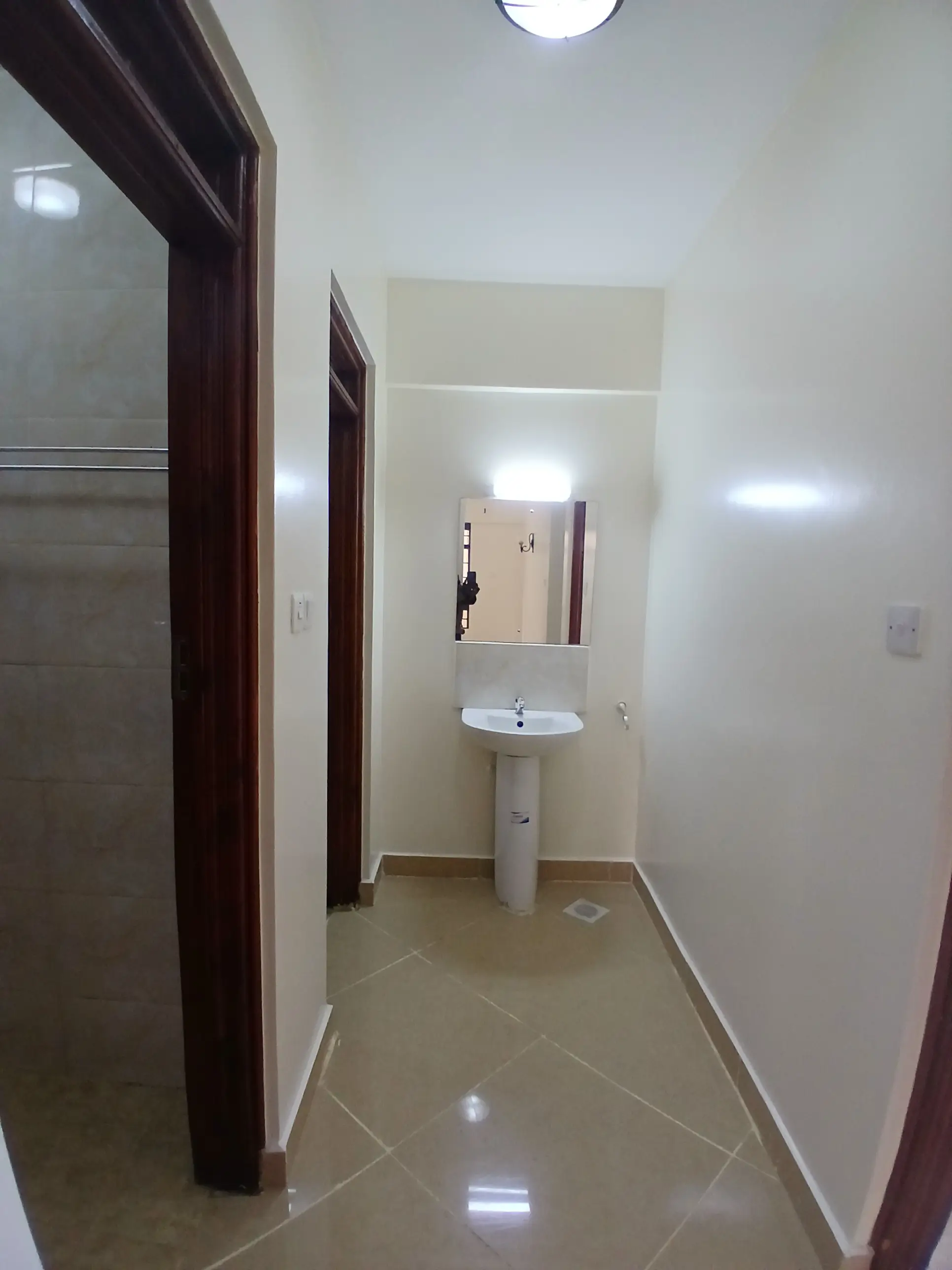 Compact bathroom with pedestal sink and dark wooden doors