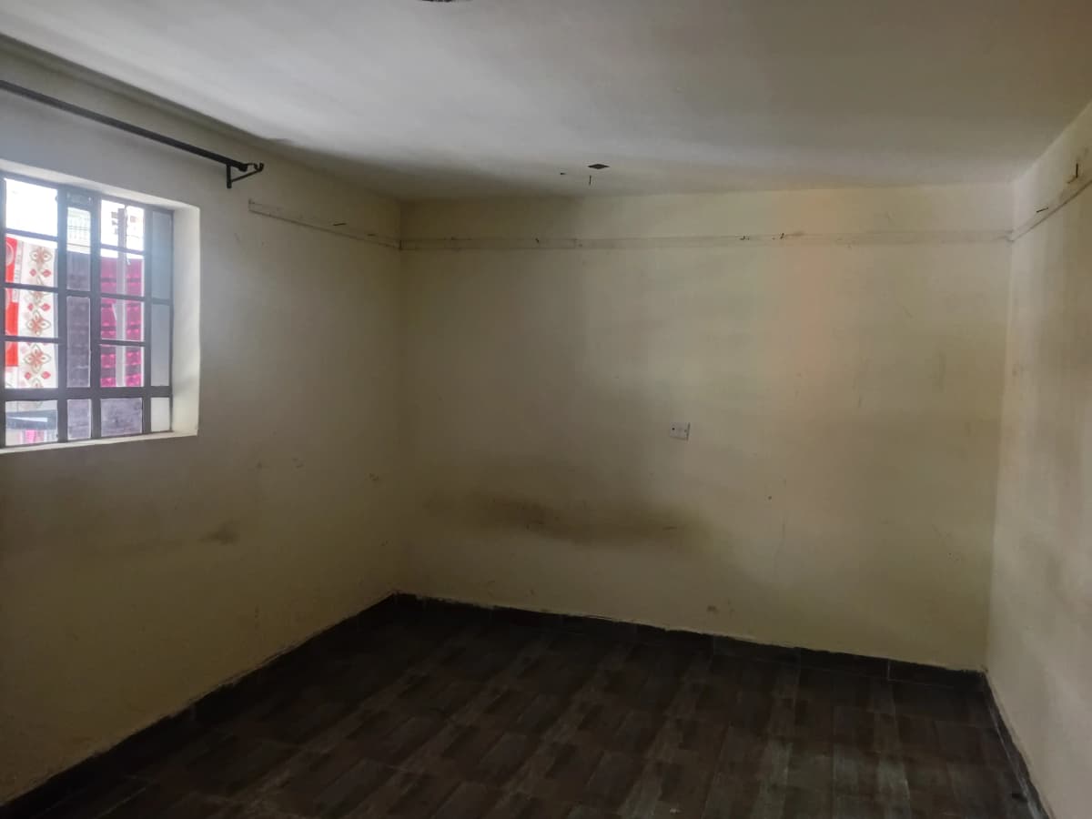 Empty bedroom with single window and dark flooring