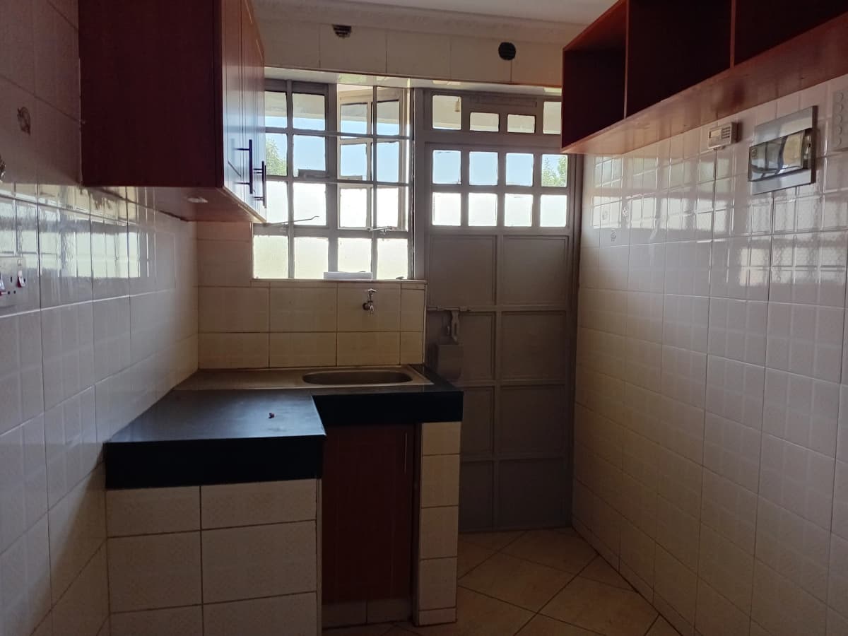 Compact kitchen with dark countertop and white tile walls
