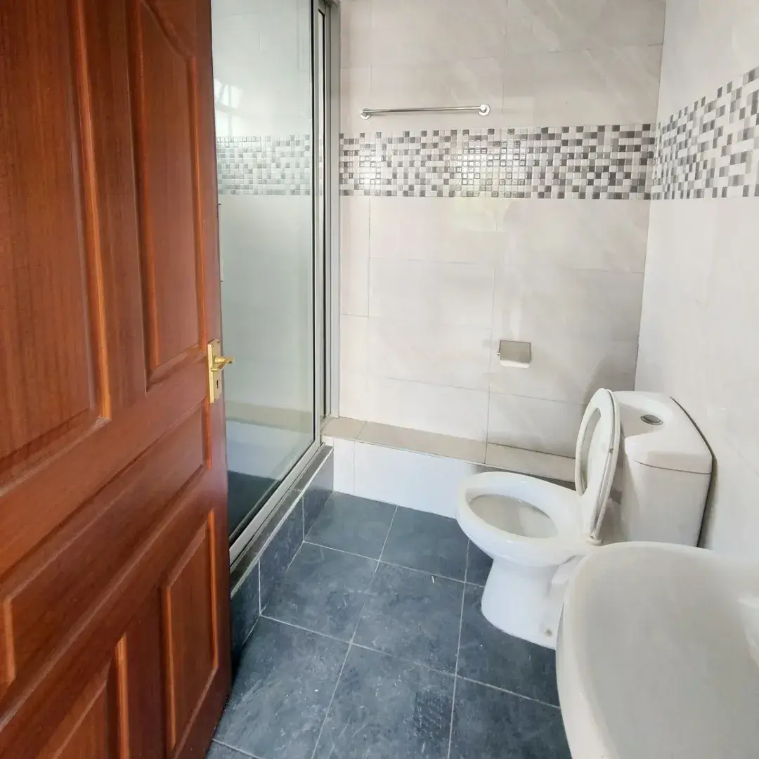 Modern bathroom with dual toilets, shower enclosure, mosaic tile accents