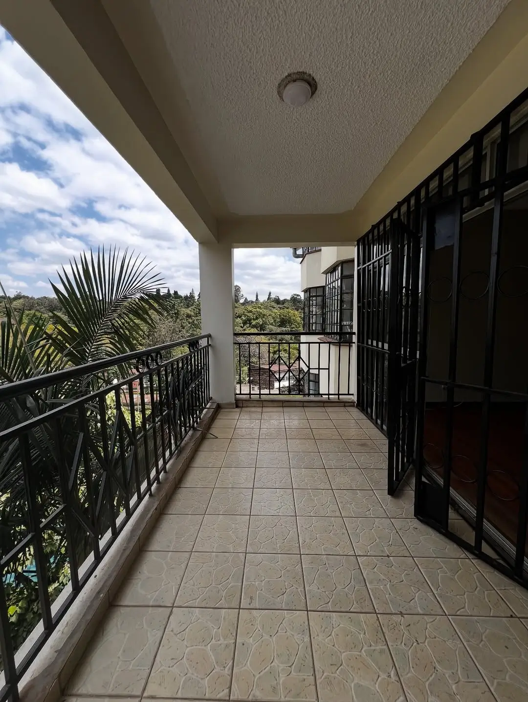 Covered balcony with black railing and garden views