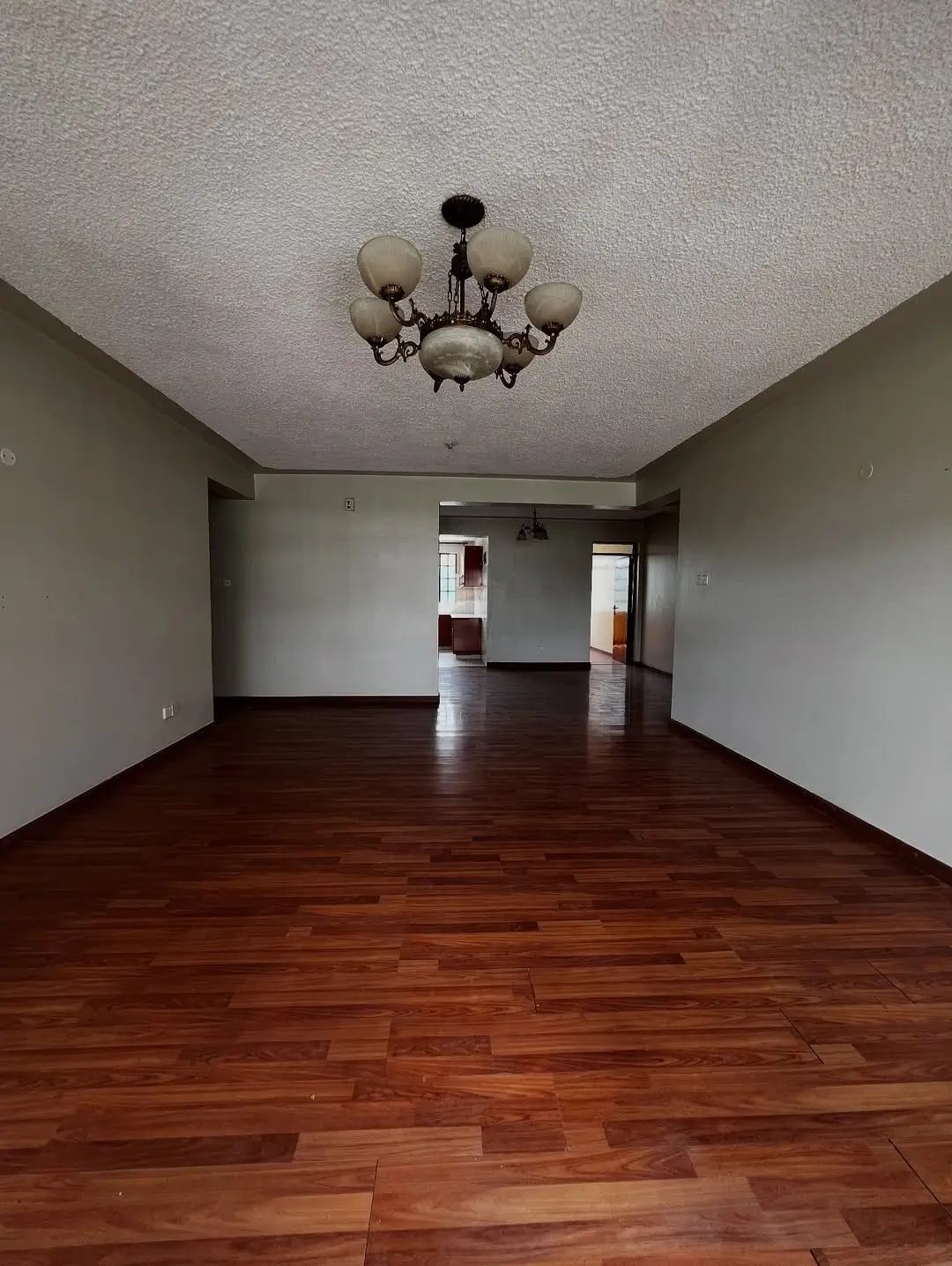 Spacious empty living room with wooden flooring and chandelier