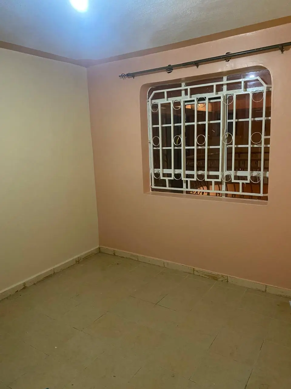 Empty bedroom with barred window and cream walls