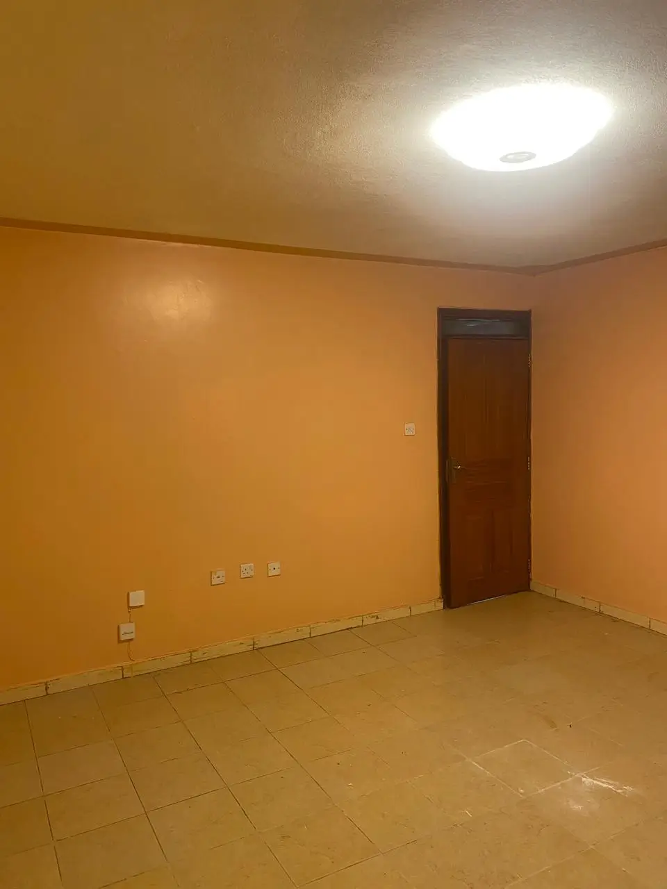 Empty room with orange walls and tiled flooring