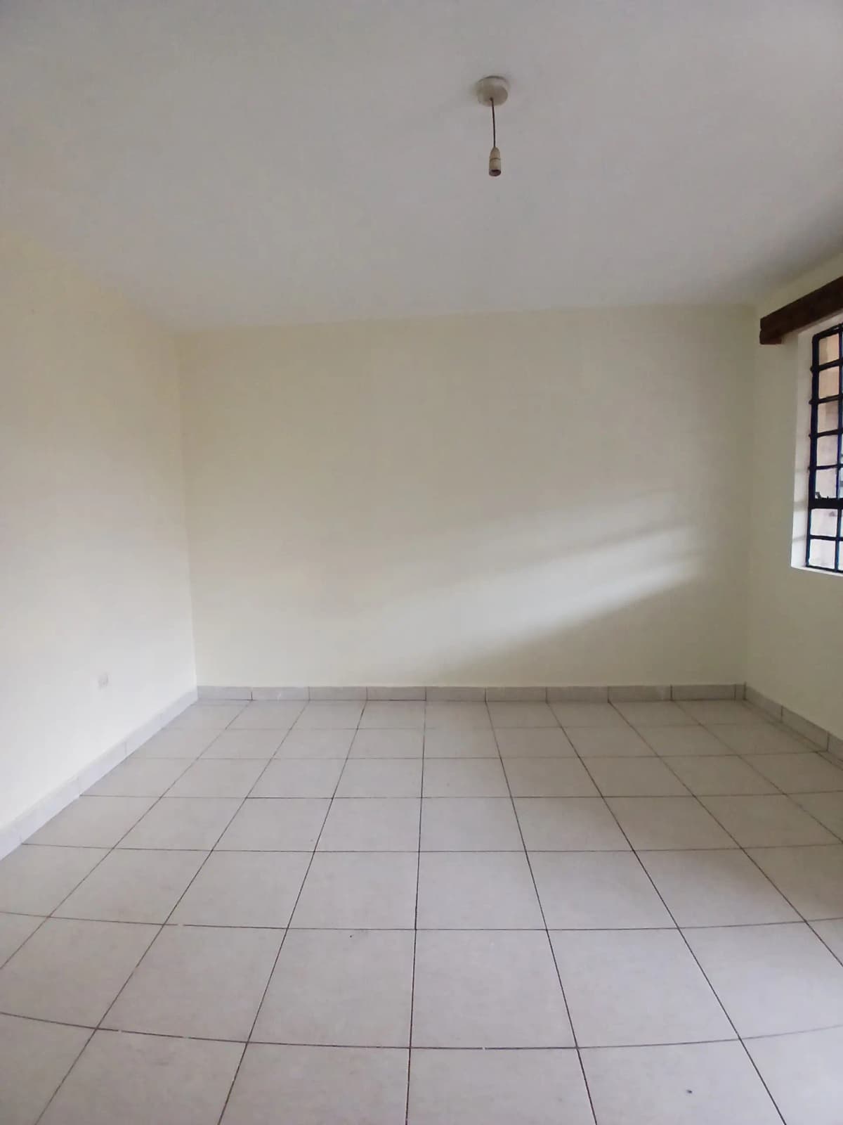 Empty bedroom with tiled floor and natural light window