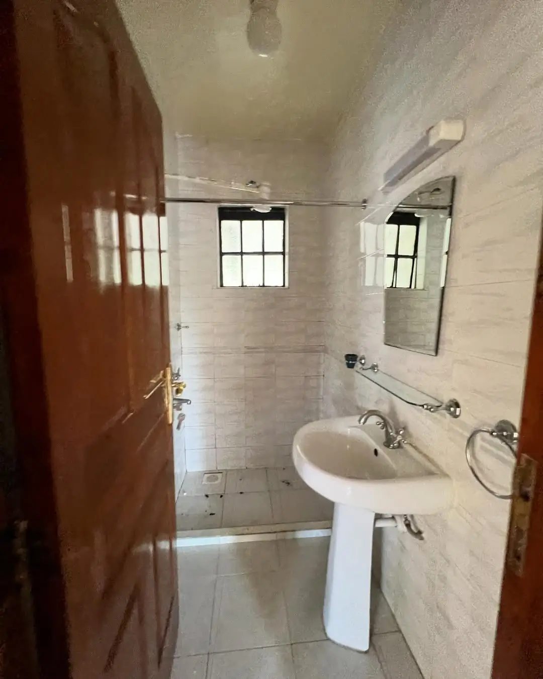 Clean bathroom with pedestal sink and tiled shower area