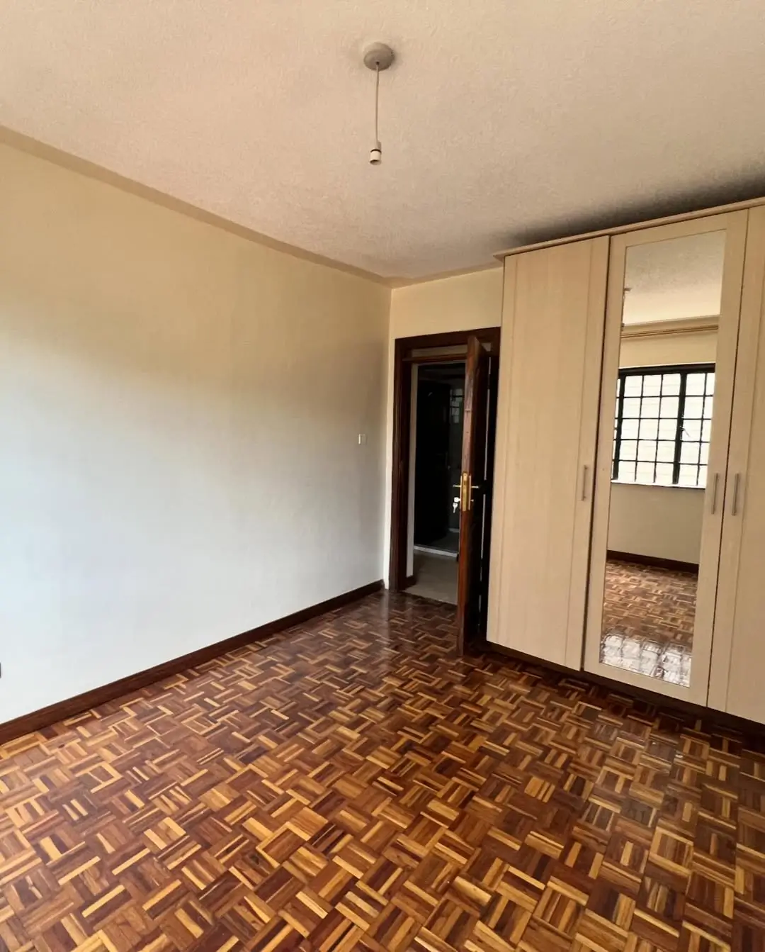 Spacious bedroom with herringbone wood flooring and built-in wardrobe