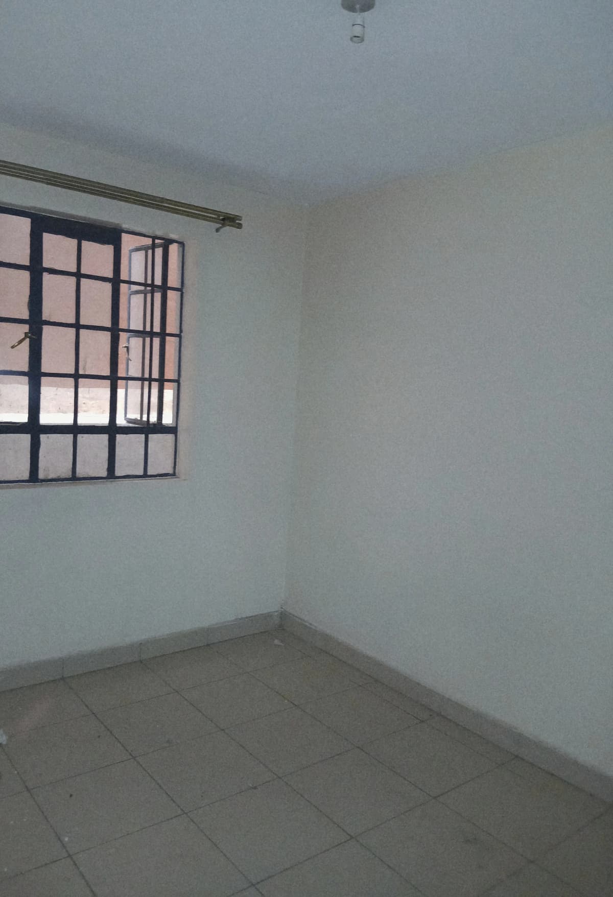 Bare bedroom with barred window and tiled floor