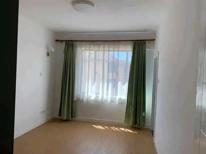 Bright bedroom with green curtains and wooden flooring