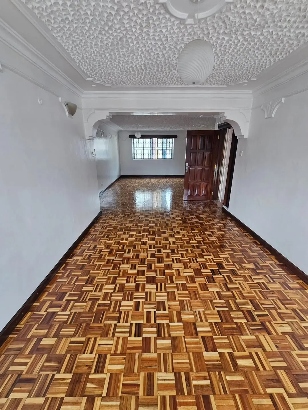Spacious empty living room with parquet flooring and textured ceiling