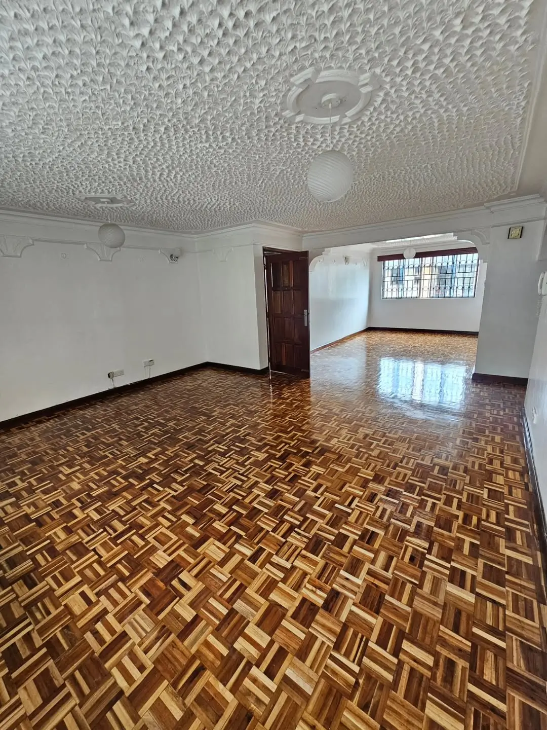 Spacious empty living room with herringbone wooden floors