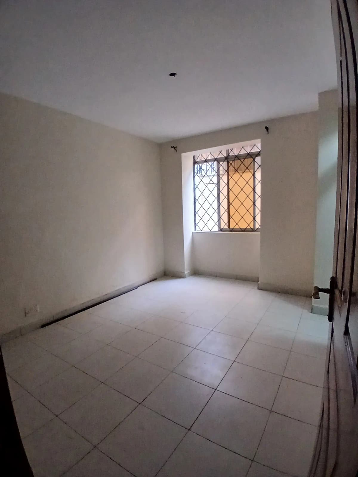 Unfurnished bedroom with tiled floor and barred window