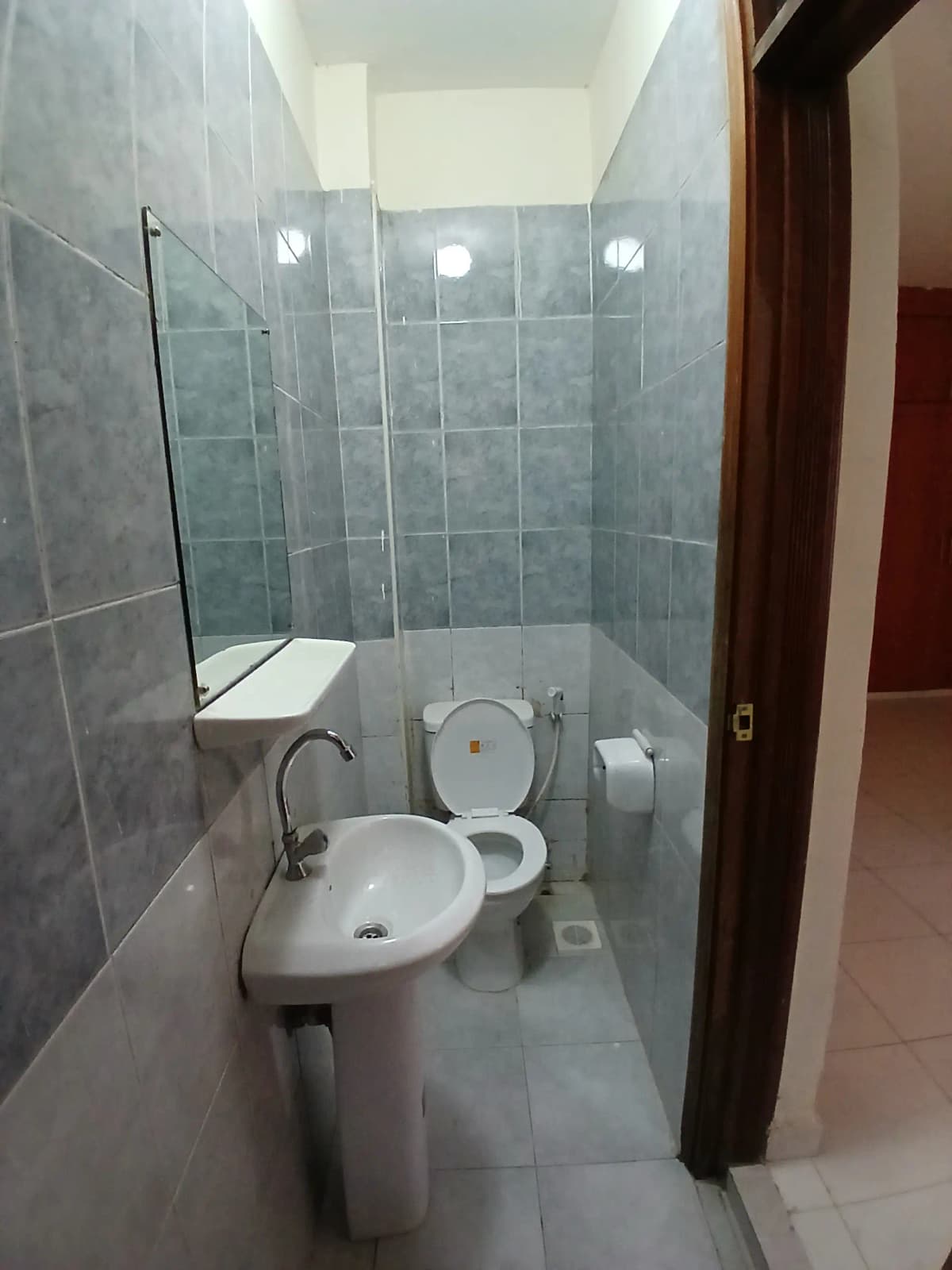 Compact bathroom with pedestal sink, toilet, and shower enclosure