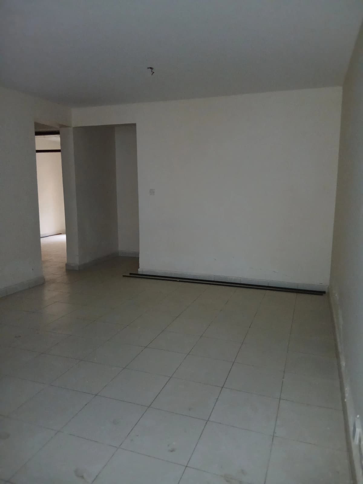 Spacious empty living room with tiled flooring and natural light