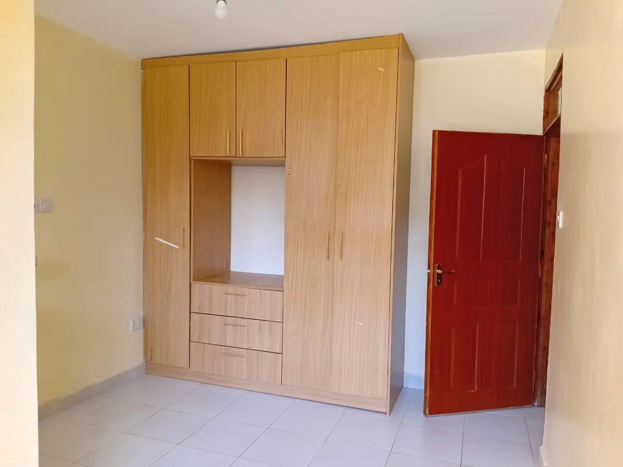 Bedroom with built-in wooden wardrobe and red door