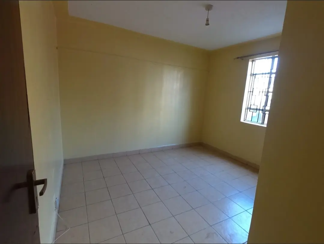 Bright bedroom with tiled flooring and barred window