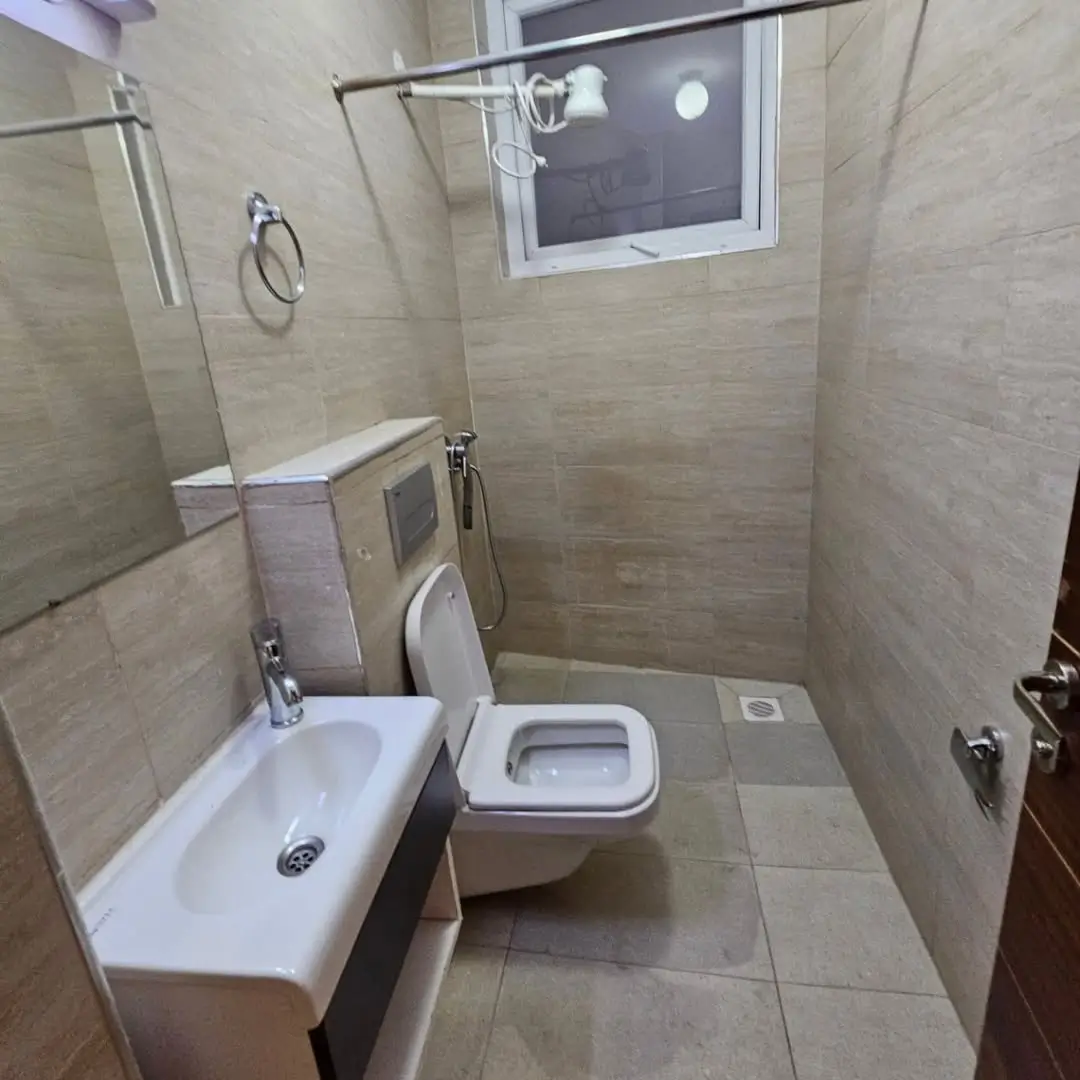 Compact bathroom with toilet, sink, and shower enclosure