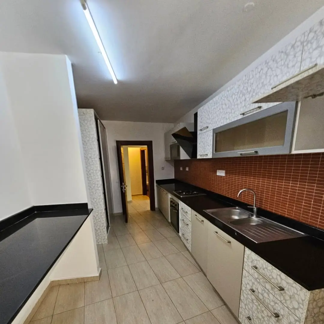 Galley kitchen with black countertops and red brick backsplash
