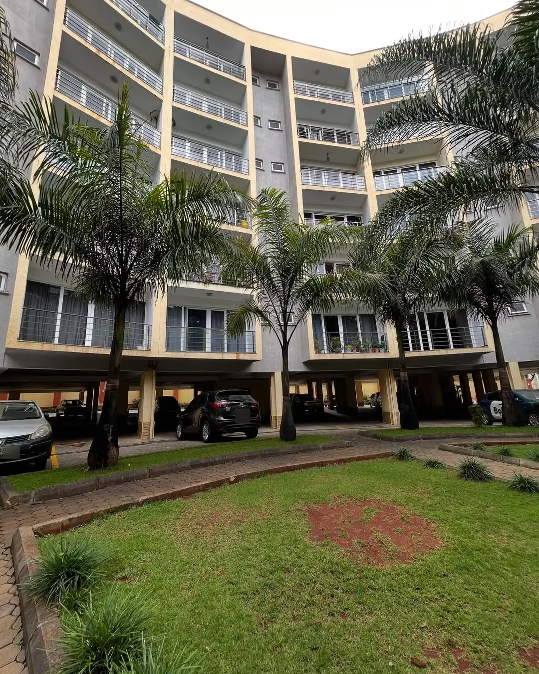 Modern multi-story residential building with landscaped compound grounds