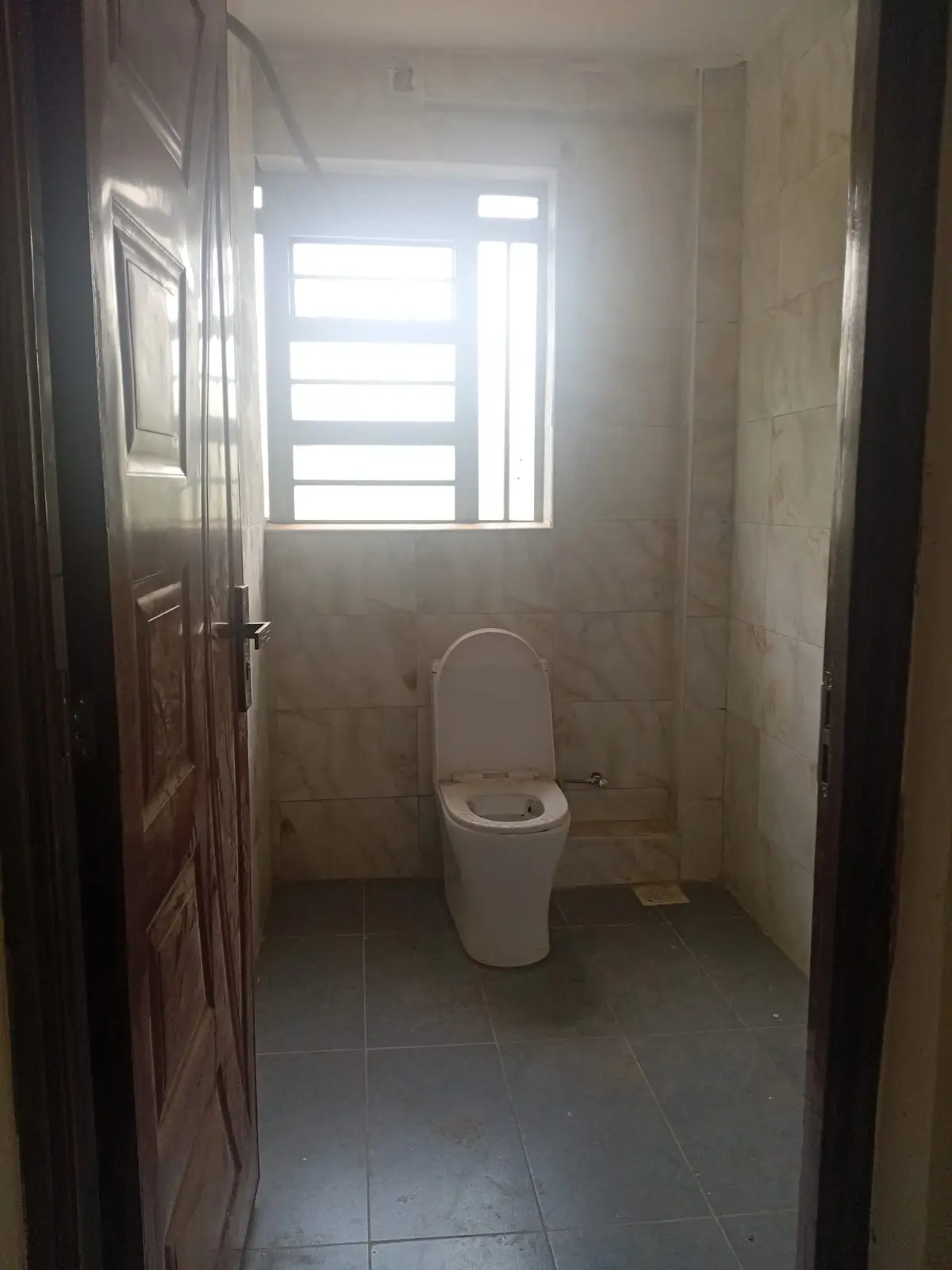 Bathroom with standalone toilet and window.