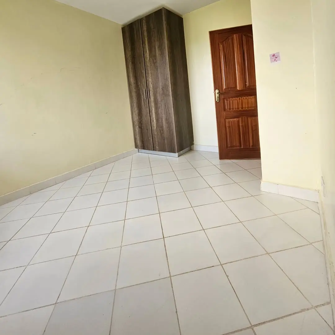Spacious empty bedroom with tiled floor and wooden wardrobe
