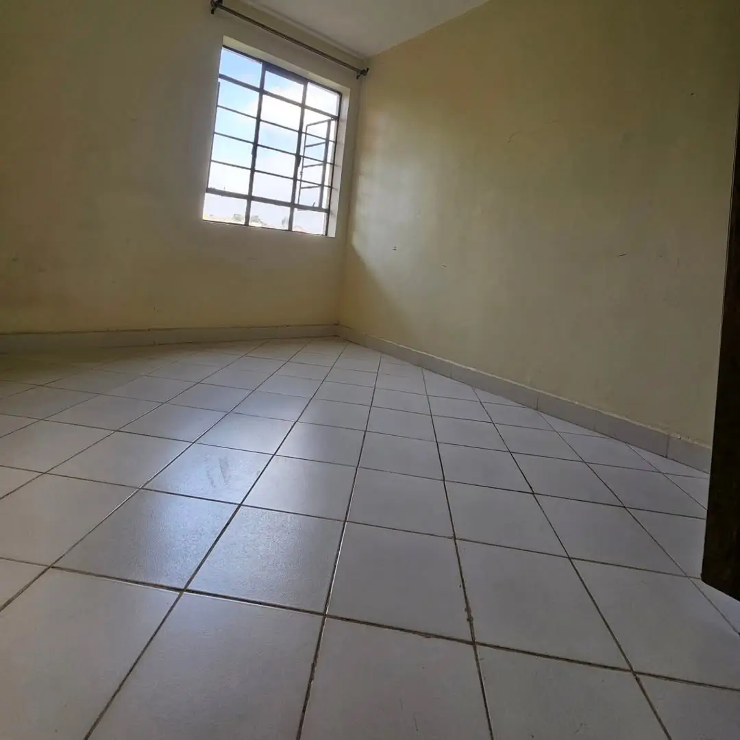 Empty bedroom with tiled floor and barred window