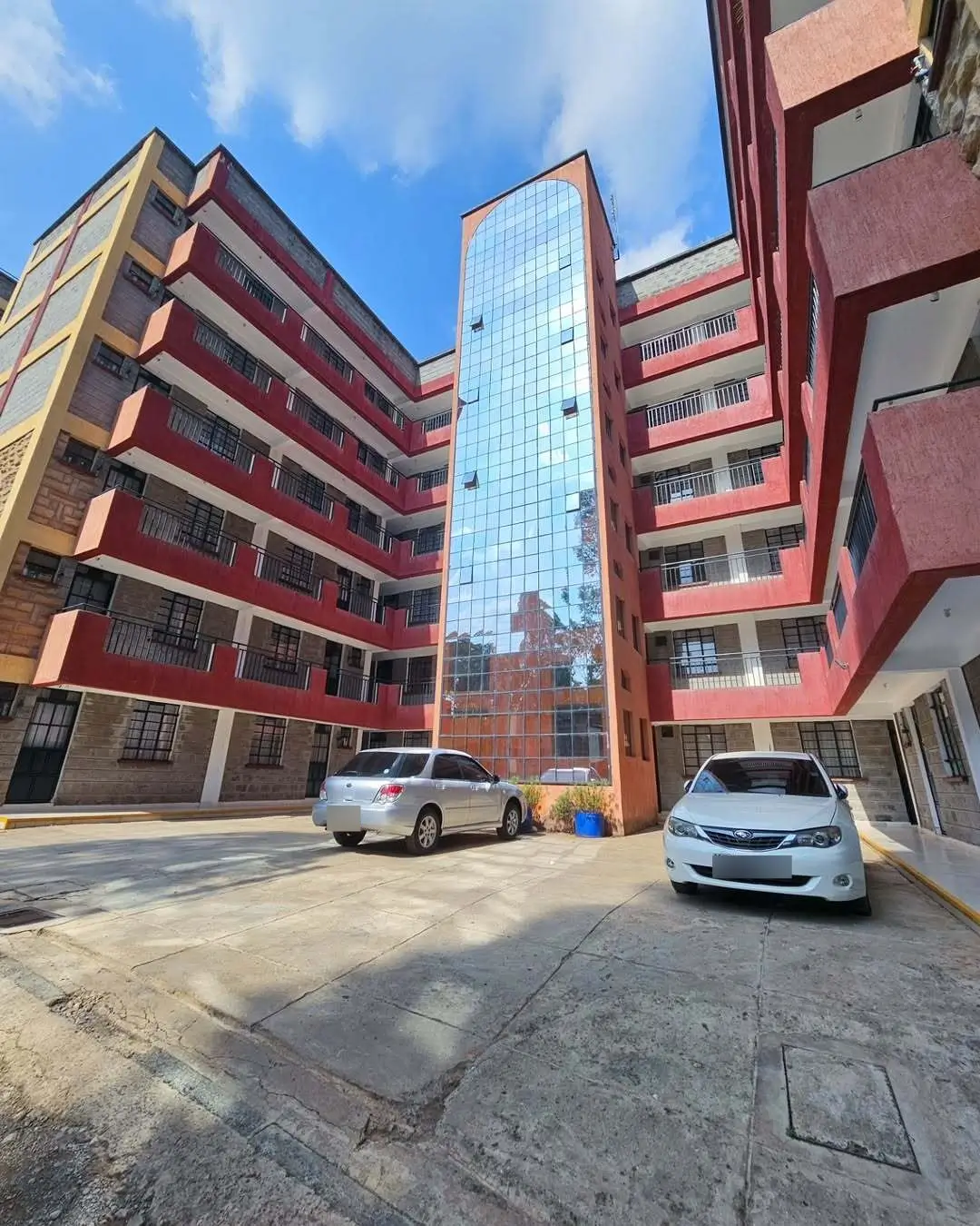 Multi-story residential complex with shared courtyard and parked vehicles