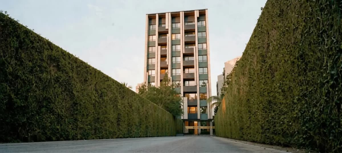 Tall apartment block framed by tall manicured hedges