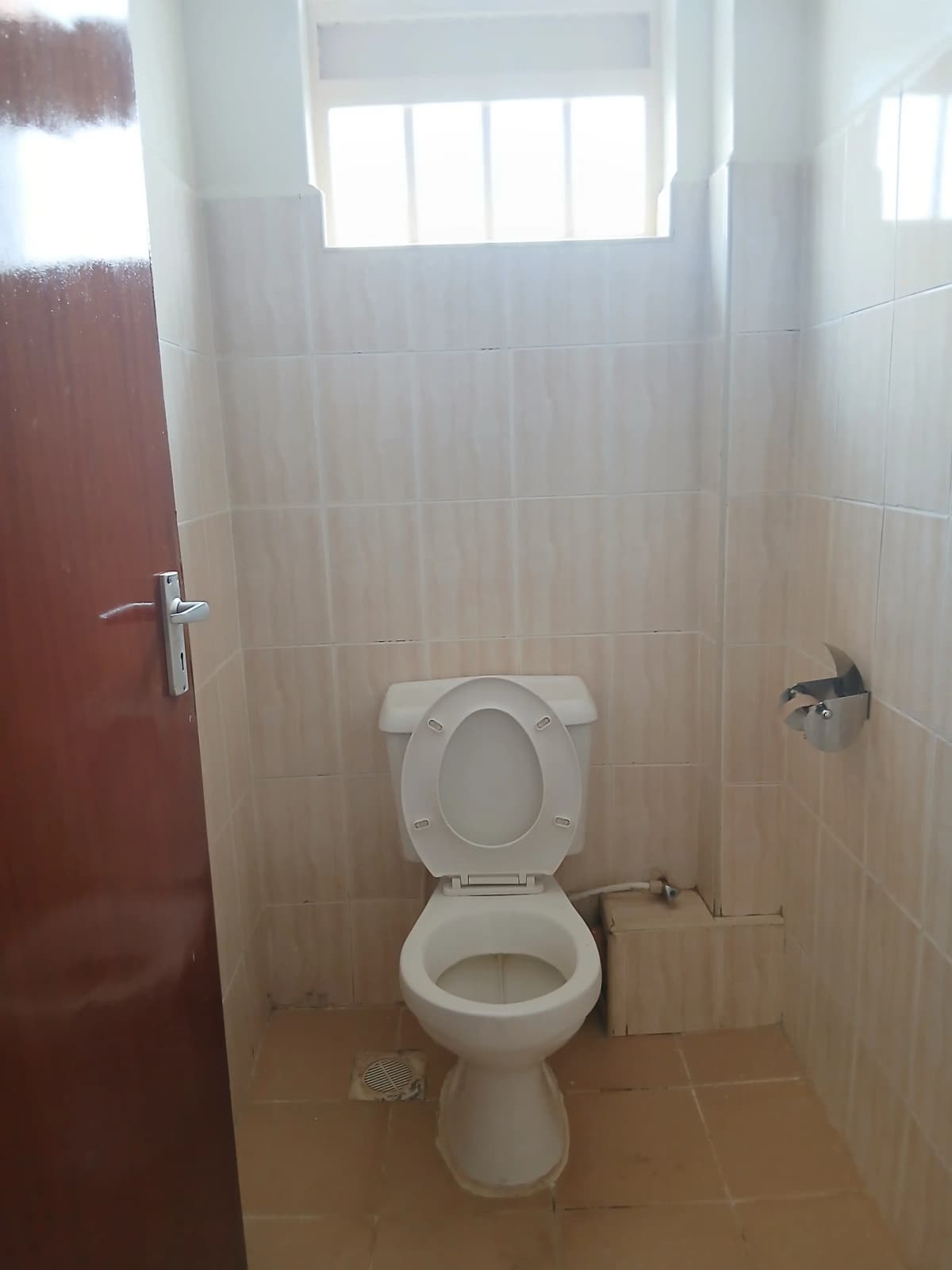 Compact toilet room with ceramic suite and high window