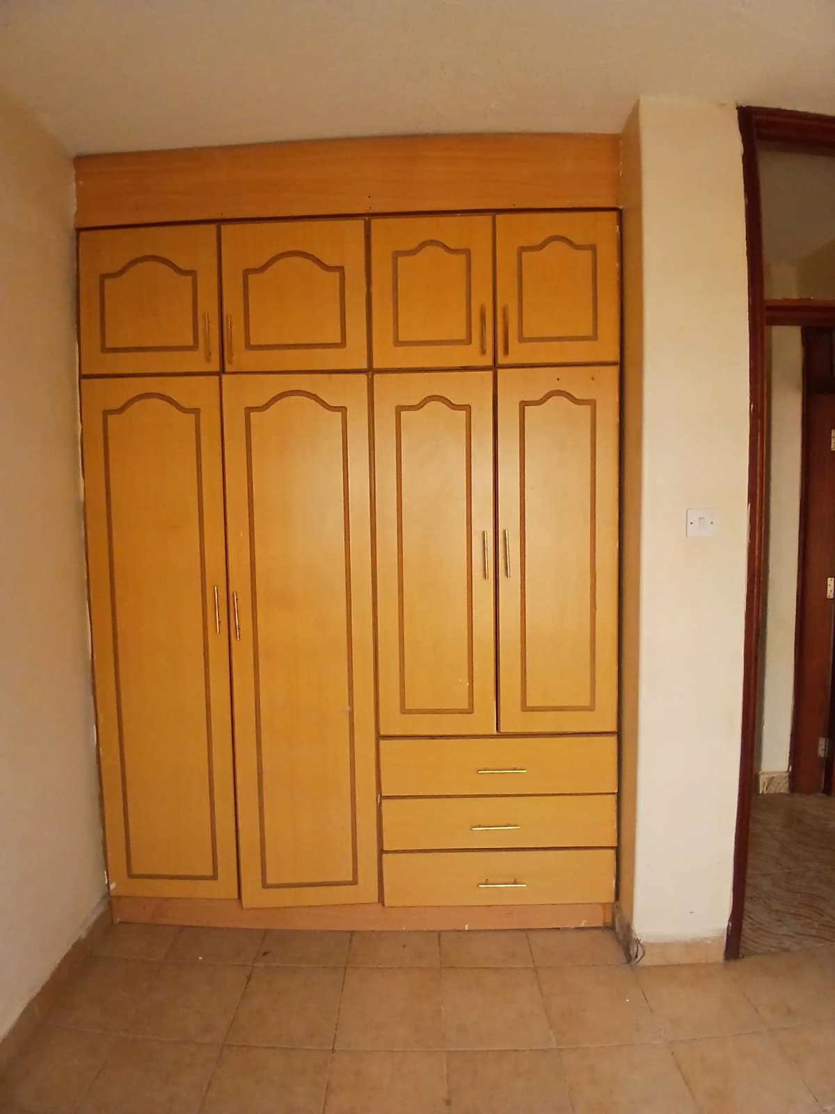 Bedroom with large wooden wardrobe and tiled floor