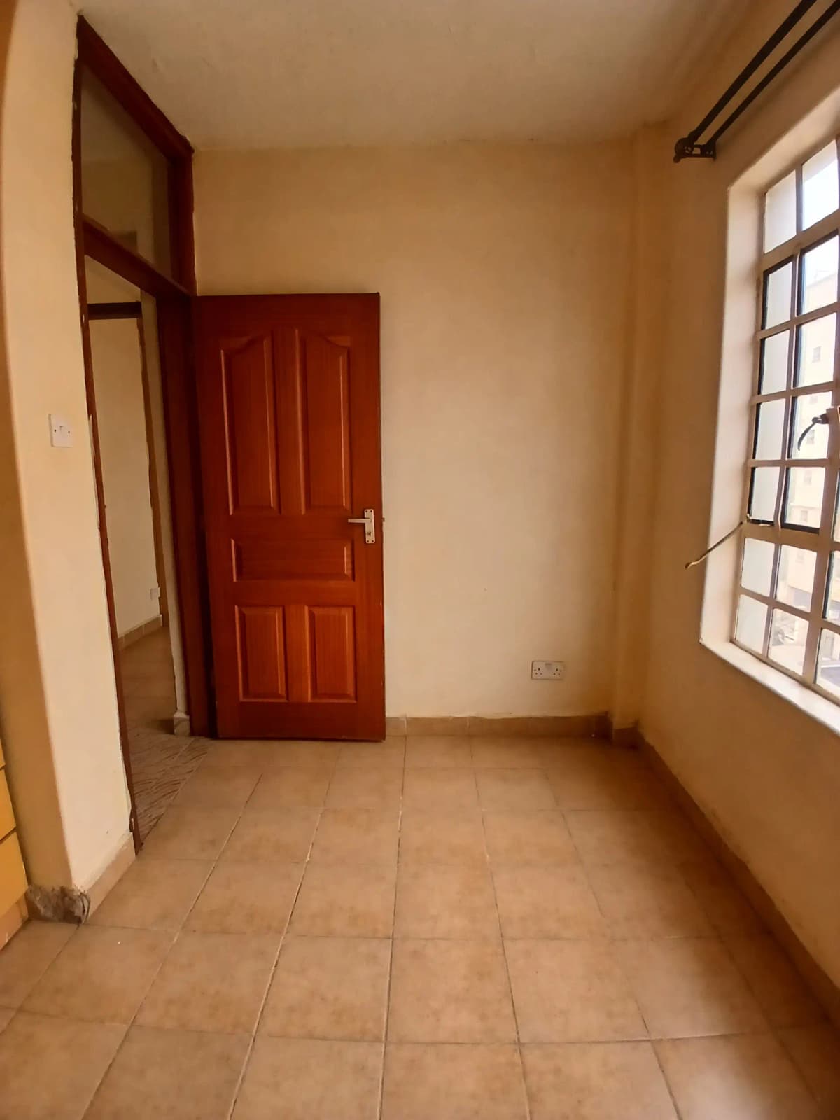 Empty bedroom with terracotta tiles and red wooden door