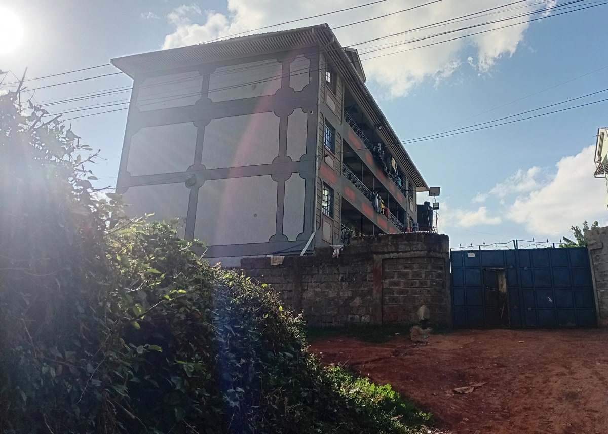 Multi-story residential building with red soil compound entrance