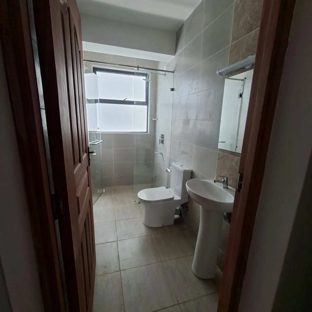 Unfurnished bathroom with glass shower, toilet, pedestal sink